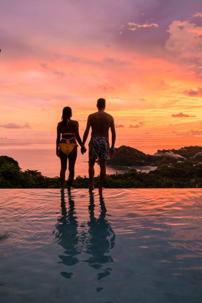 Romantic couple of men and women at a swimming pool during a vacation on a tropical island